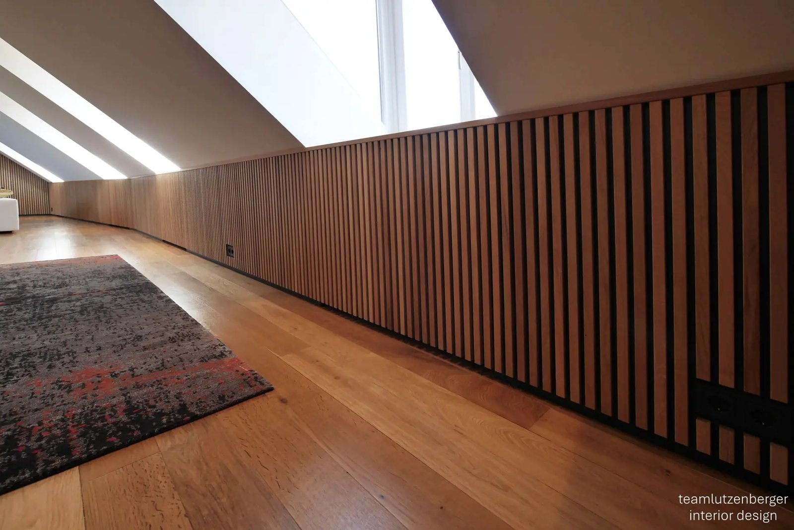 Wohnraum unter der Dachschräge mit raumhoher Wandverkleidung aus Eichenleisten
